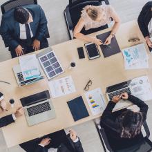 Vista a&eacute;rea de una mesa de reuniones en que hay varias personas con ordenadores port&aacute;tiles, debatiendo la respuesta ante un incidentes de seguridad digital.