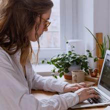 Una mujer trabajando en remoto con un ordenador.