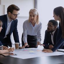 Hainbat pertsona mahai baten inguruan, arrisku digitalen kudeaketari buruz hitz egiten.