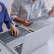 Dos t&eacute;cnicos en un ordenador al que se le est&aacute;n instalando parches de seguridad y actualizaciones.