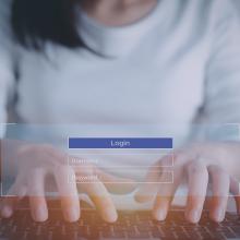 Emakume baten eskuak pasahitza sartzen ordenagailu batean.