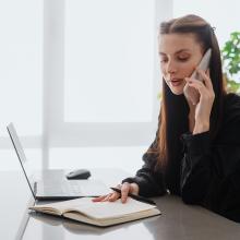 Mujer en una oficina habla por un m&oacute;vil para recibir informaci&oacute;n de los requisitos de ciberseguridad para el aut&oacute;nomo en la Industria.
