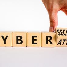 Un dedo sobre unos cubos con letras que forman la expresi&oacute;n "cyber attack".