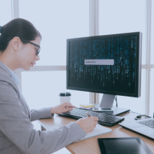 Una mujer frente a la pantalla de un ordenador inform&aacute;ndose sobre la securizaci&oacute;n de los accesos remotos OT.