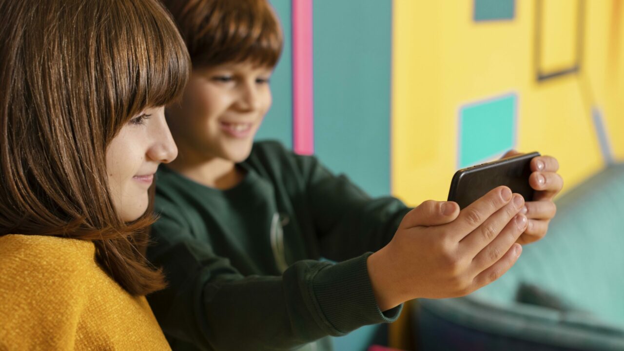 Dos menores mirando un m&oacute;vil, felices por la campa&ntilde;a lanzada por Cyberzaintza para frenar el acoso y proteger a los m&aacute;s j&oacute;venes.