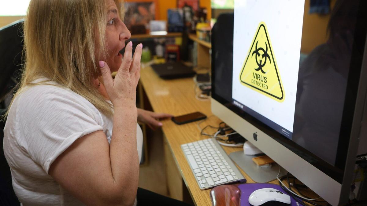 Harridura-keinua egiten emakume bat ordenagailu baten pantailaren aurrean, non hackeatu dutela dioen abisu bat agertzen den.