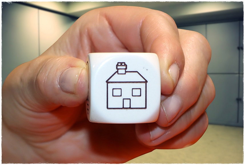 Imagen de una mano sosteniendo un dado grande con el dibujo de una casita