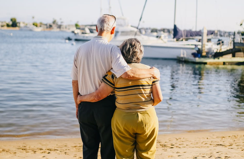 Imagen de una pareja de ancianos (hombre y mujer) abrazados frente al mar.