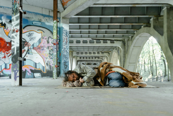 Hombre sin hogar durmiendo sobre un cartón y bajo un puente