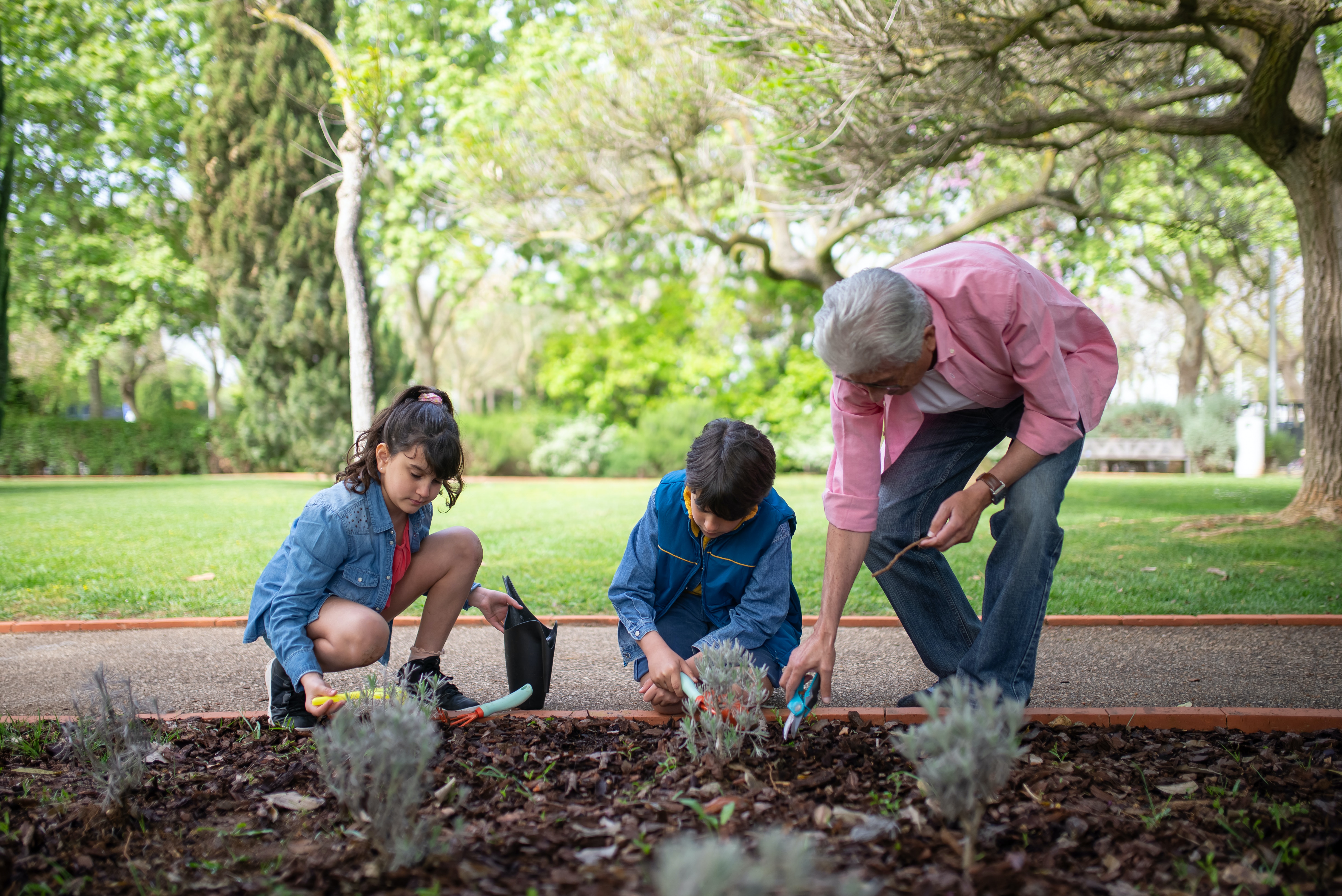 Dos menores haciendo jardiner&iacute;a con hombre mayor